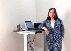 Founder standing next to a standing desk with a laptop and office supplies.