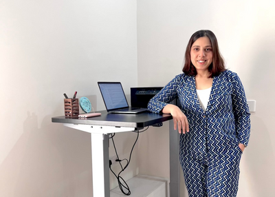 Founder standing next to a standing desk with a laptop and office supplies.
